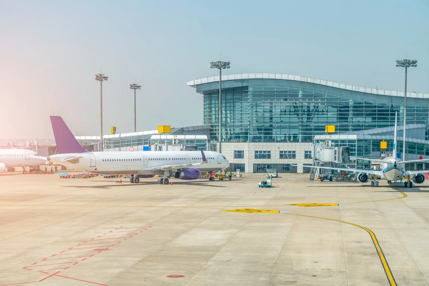 Parked aircraft beside a glass airport terminal