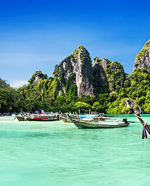 Longtail boats beside limestone cliffs