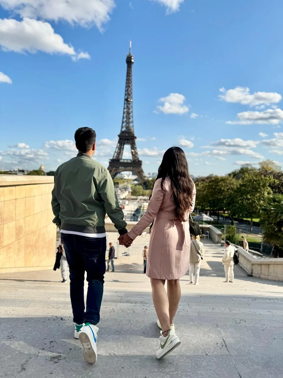 Couple holding hands near the Eiffel Tower in Paris